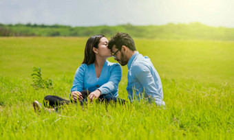 浪漫的夫妇坐着草接吻额头漂亮的女孩接吻男朋友的额头场夫妇爱坐着场接吻额头