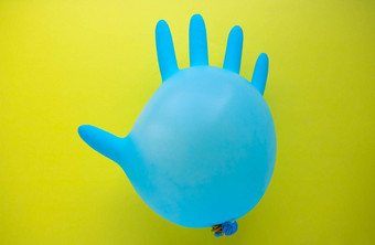 飞行蓝色的橡胶<strong>外科手术手套</strong>形式气球黄色的背景复制空间概念极简主义