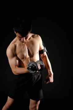 运动肌肉发达的健美运动员男人。聪明的移动电话手镯工作哑铃健身锻炼概念
