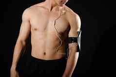 运动肌肉发达的健美运动员男人。聪明的电话手镯听音乐健身锻炼概念
