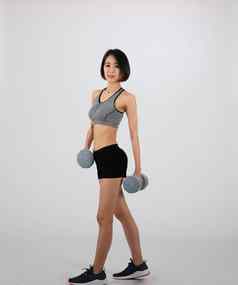 运动女人运动服装哑铃健身锻炼白色背景健康的体育运动生活方式
