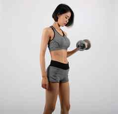 运动女人运动服装哑铃健身锻炼白色背景健康的体育运动生活方式