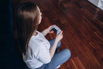年轻的女人玩游戏控制台女孩玩家电脑视频游戏彩带持有操纵杆手人首页晚上