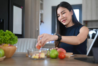 健康的年轻的女人使素食主义者餐新鲜的<strong>蔬菜水果</strong>厨房