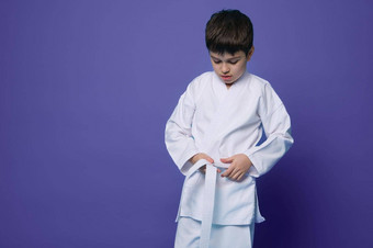 水平肖像自信十几岁的男孩合气道摔跤手系白色带和服孤立的紫罗兰色的背景复制空间