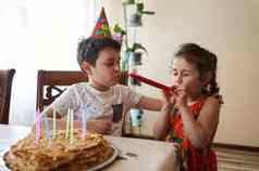 迷人的可爱的高加索人孩子们庆祝生日聚会，派对首页手工制作的烤生日蛋糕色彩斑斓的蜡烛厨房表格