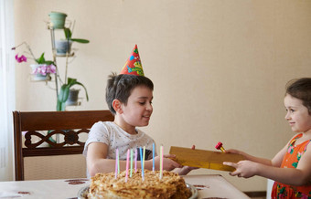 迷人的高加索人男孩接<strong>收礼</strong>物年轻的妹妹生日坐在表格生日蛋糕蜡烛生日周年纪念日事件庆祝活动概念
