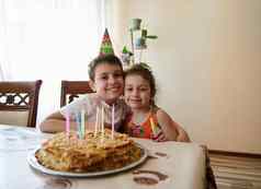 肖像可爱的可爱的孩子们哥哥妹妹坐着表格生日蛋糕装饰长色彩斑斓的蜡烛周年纪念日生日聚会，派对概念