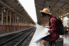 漂亮的年轻的旅行者女人地图规划旅行火车站夏天旅行生活方式概念