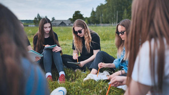 集团女学生坐着圆草地集体工作笔记本电脑