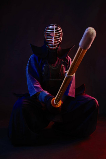 关闭剑道战斗机穿护甲传统的和服头盔坐着练习武术艺术shinai竹子剑黑色的背景