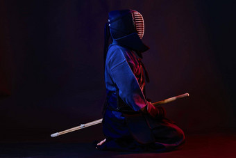 关闭拍摄剑道战斗机穿护甲传统的和服头盔练习武术艺术shinai竹子剑黑色的背景