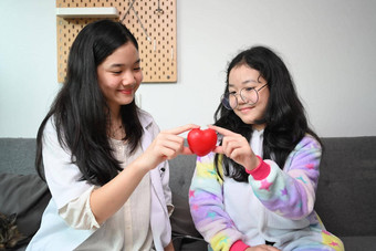微笑亚洲女孩持有红色的心爱护理健康护理概念