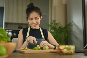 美丽的年轻的女人使素食者蔬菜沙拉首页厨房