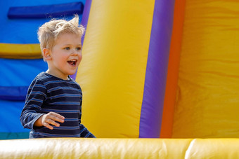 孩子跳充气反弹城堡幼儿园生日聚会，派对活动玩中心年轻的孩子微笑男孩玩在户外夏天