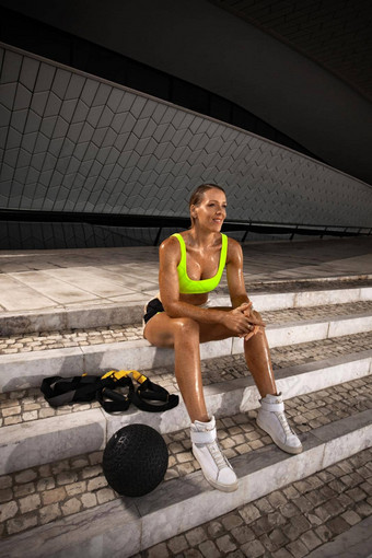 女人健身穿休息锻炼重医学球trx肩带在户外运动女孩适合身体运动服装摆姿势楼梯
