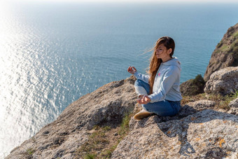 女人旅游享受日落海山景观坐在在户外岩石海穿牛仔裤蓝色的连帽衫<strong>健康</strong>的生活方式<strong>和谐</strong>冥想