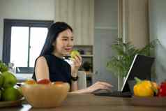 有吸引力的女人吃苹果电脑平板电脑厨房健康的生活方式健康的食物概念