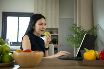 有吸引力的女人吃<strong>苹果电脑</strong>平板电脑厨房健康的生活方式健康的食物概念