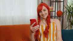 快乐的红色头发的人女孩坐着沙发智能手机分享消息社会媒体应用程序