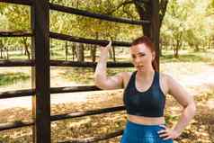 肖像年轻的女运动员倾斜公共格子运动员练习体育运动在户外休息培训健康健康生活方式
