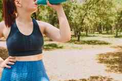 裁剪拍摄年轻的健身女孩喝水刷新瓶体育锻炼女孩练习体育运动在户外健康健康生活方式