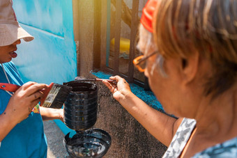 拉丁妈妈。女儿加载油漆<strong>塑料桶</strong>工作改造房子