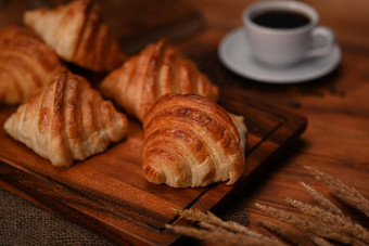 美味的黄油羊角面包黑色的木表格热咖啡悬浮面包面包店产品咖啡馆概念