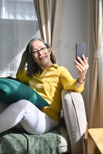 微笑中间岁的女人持有智能手机使<strong>视频</strong>调用朋友亲戚享受愉快的谈话首页