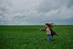 女人外套走绿色场多雨的天气强大的风和谐自然