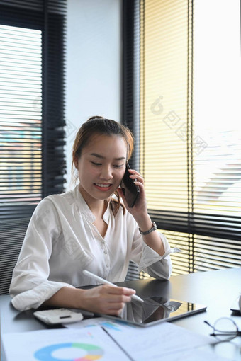 年轻的女金融顾问电话谈话客户端数字平板电脑工作场所