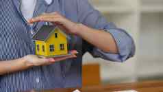 女人手庇护小房子模型真正的房地产投资者租赁保险购买销售合同维护概念
