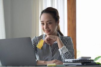 有吸引力的女人持有信贷卡互联网银行服务支付账单在线电脑移动PC