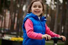 快乐的微笑快乐欧洲孩子可爱的女孩游乐设施踢踏板车城市公园休闲活动快乐无忧无虑的童年活跃的健康的生活方式概念
