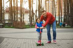 快乐友好的家庭迷人的爱的父亲一年女儿骑推踏板车在户外森林公园活跃的生活方式为人父母童年