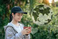 亚洲女孩持有盆栽植物全息图地球模糊绿色自然背景地球一天生态概念