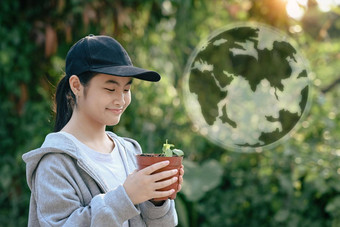 亚洲女孩持有盆栽植物<strong>全息</strong>图<strong>地球</strong>模糊绿色自然背景<strong>地球</strong>一天生态概念