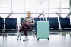 深思熟虑的女人行李坐着机场等待房间