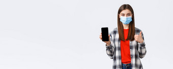 情绪科维德社会距离技术概念满意年轻的自信女孩推荐应用程序购物网站显示移动电话屏幕竖起大拇指