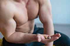不知名的健美运动员饮料胶囊特写镜头肌肉发达的赤膊上阵男人。持有一些维生素健身补充