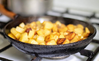 烤新鲜的土豆投铁长柄平底煎锅向日葵石油视图炉子上煎锅填满金炸土豆真正的厨房食物煮熟的自制的煎锅