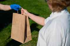 女快递手套把食物包退休女人女人将纸袋食品杂货女养老金领取者户外交付服务检疫特写镜头