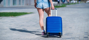 女人走卷蓝色的手提箱轮子人行道上<strong>行李</strong>街城市准备好了旅行后视图女孩短裤旅行大袋