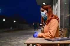 女人医疗面具手套走晚些时候晚上女孩坐着木表格移动PC检疫冠状病毒
