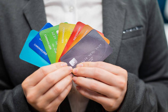 不知名的女人西装持有多色的信贷卡片银行员工显示很多塑料卡片特写镜头缺乏现金
