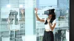 年轻的女人穿虚拟现实耳机相互作用网络空间站大窗口城市建筑视图
