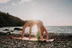 中间岁的女人黑色的头发普拉提环瑜伽席海卵石海滩女健身瑜伽概念健康的生活方式和谐冥想