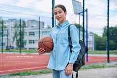 肖像十几岁的学生女孩背包篮球球