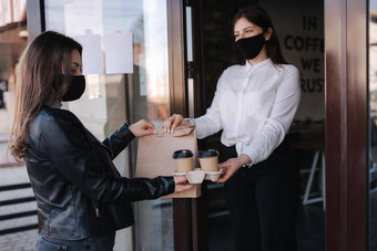 年轻的女人站在户外面具<strong>支付</strong>比尔智能手机NFC技术咖啡馆女客户<strong>支付</strong>非接触式技术女人采取订单食物概念