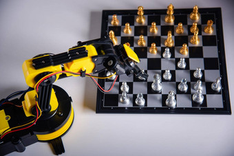 特写镜头黄色的机器人<strong>手</strong>臂玩移动国际象棋棋盘